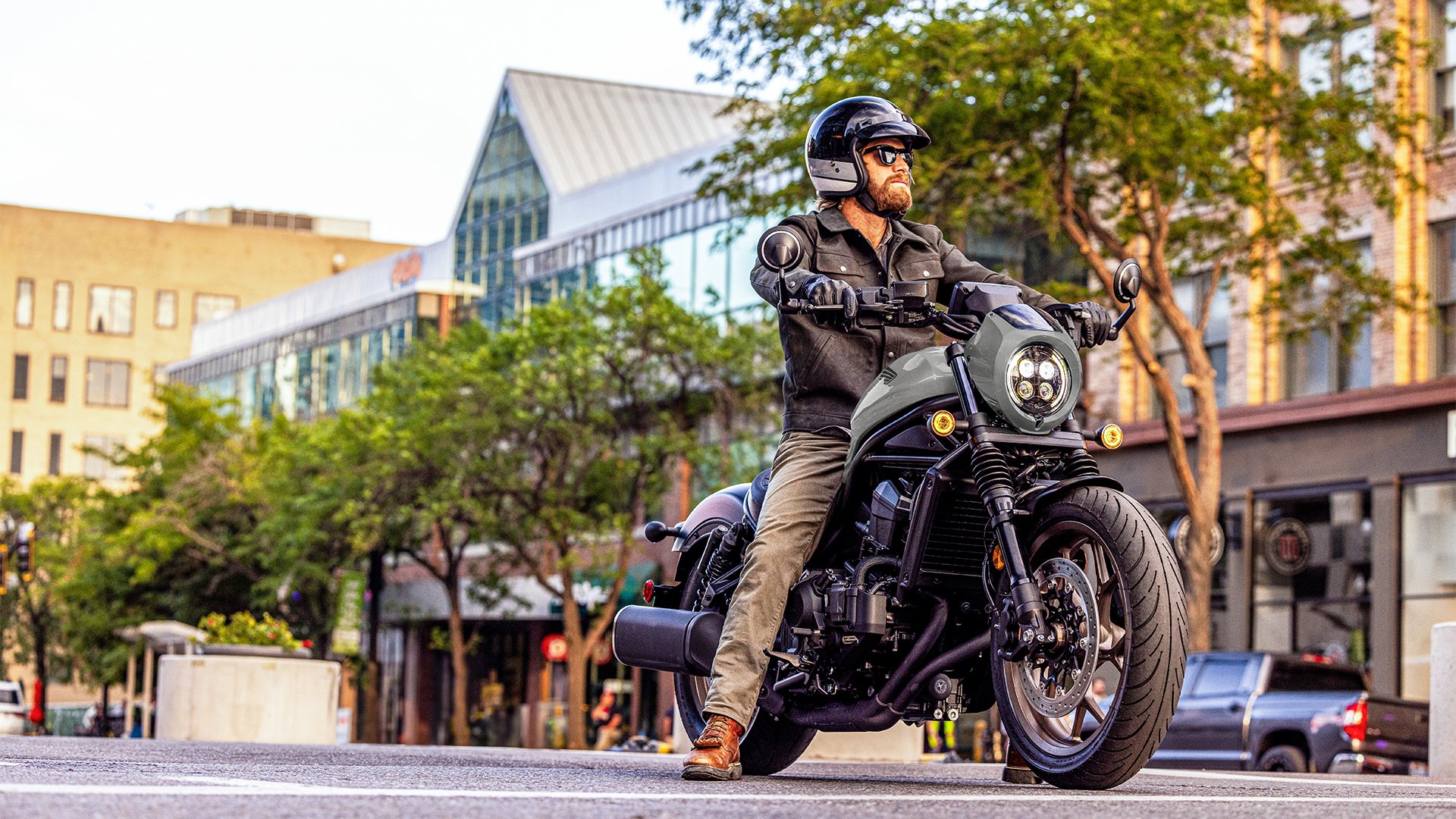 Modelo numa Honda CMX1100 voltada para a frente, num cenário urbano.