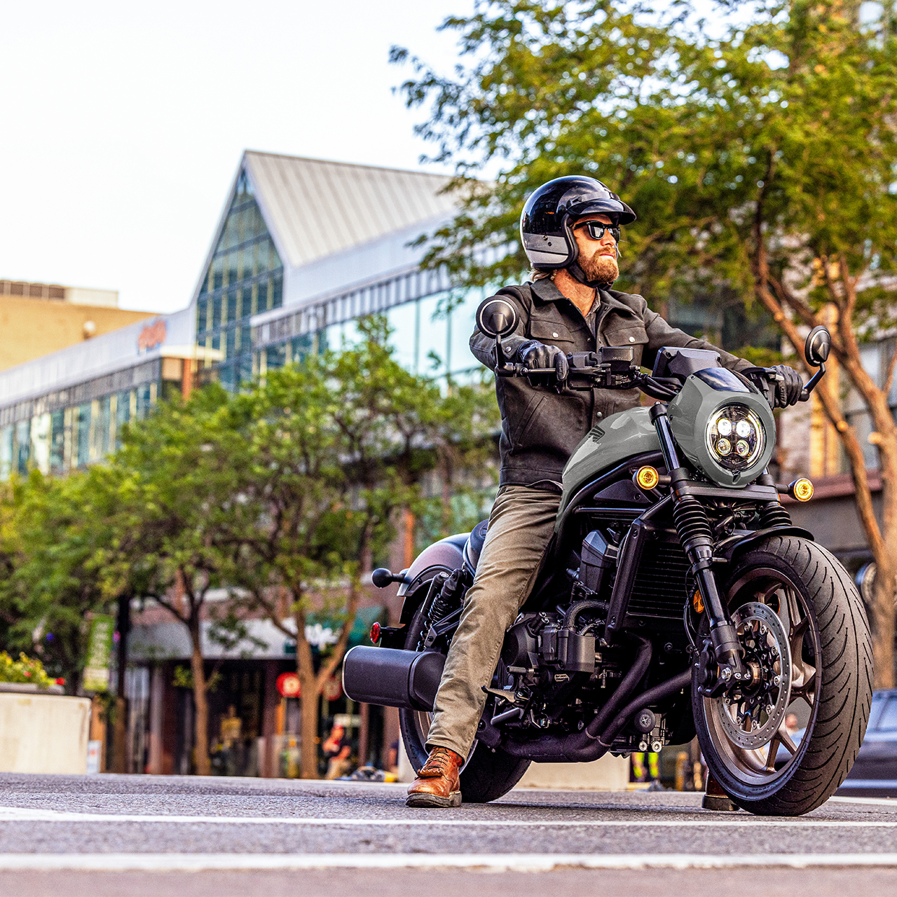 Modelo numa Honda CMX1100 voltada para a frente, num cenário urbano.