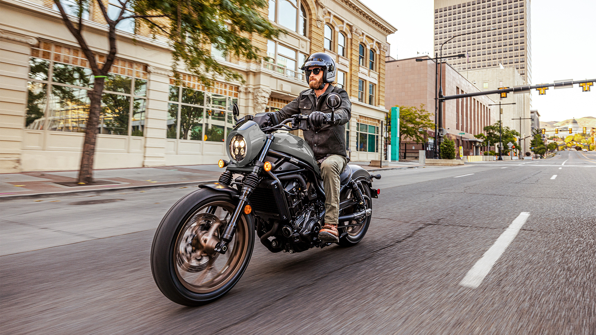 Modelo sobre uma Honda CMX1100 voltada para a frente, num cenário urbano.
