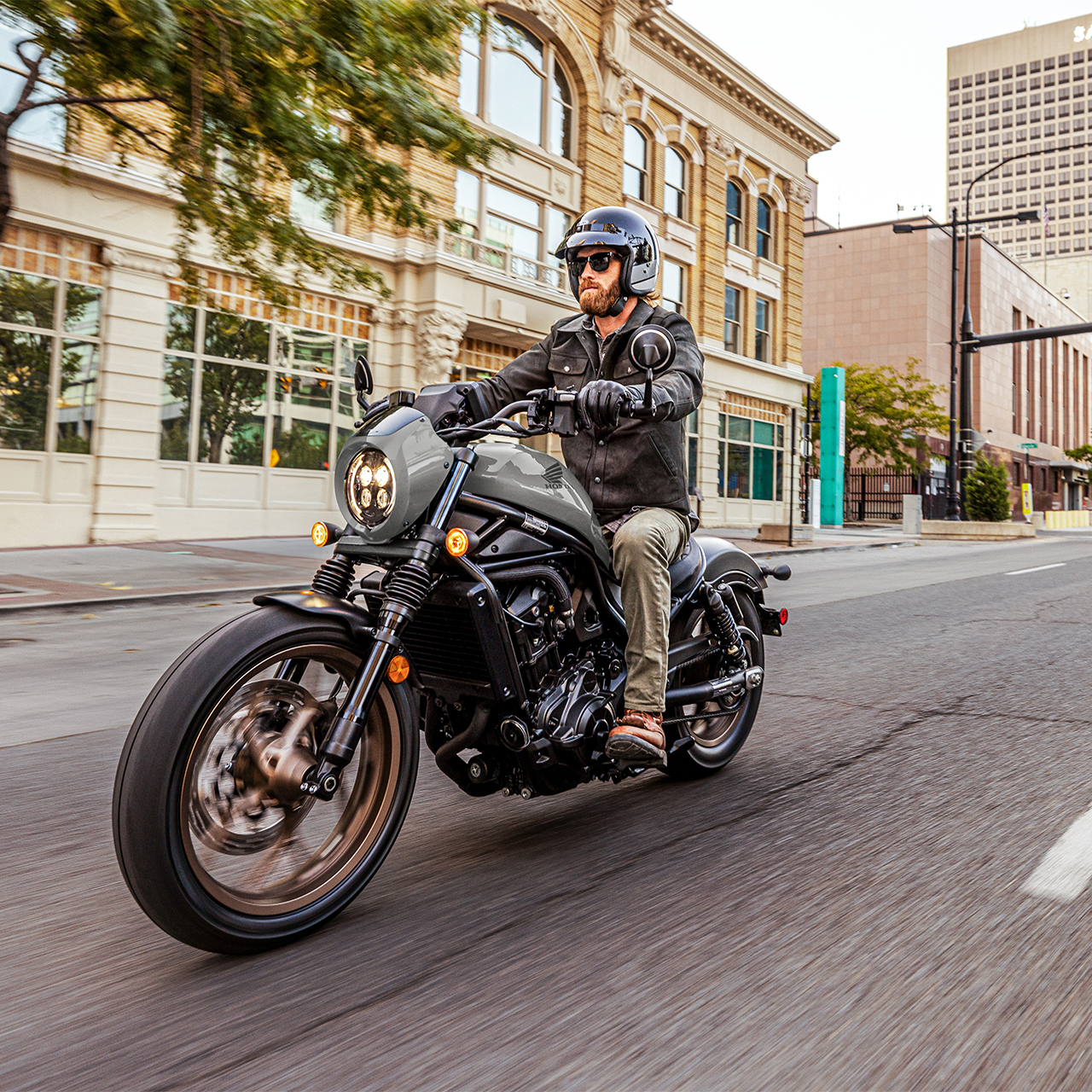 Modelo sobre uma Honda CMX1100 voltada para a frente, num cenário urbano.