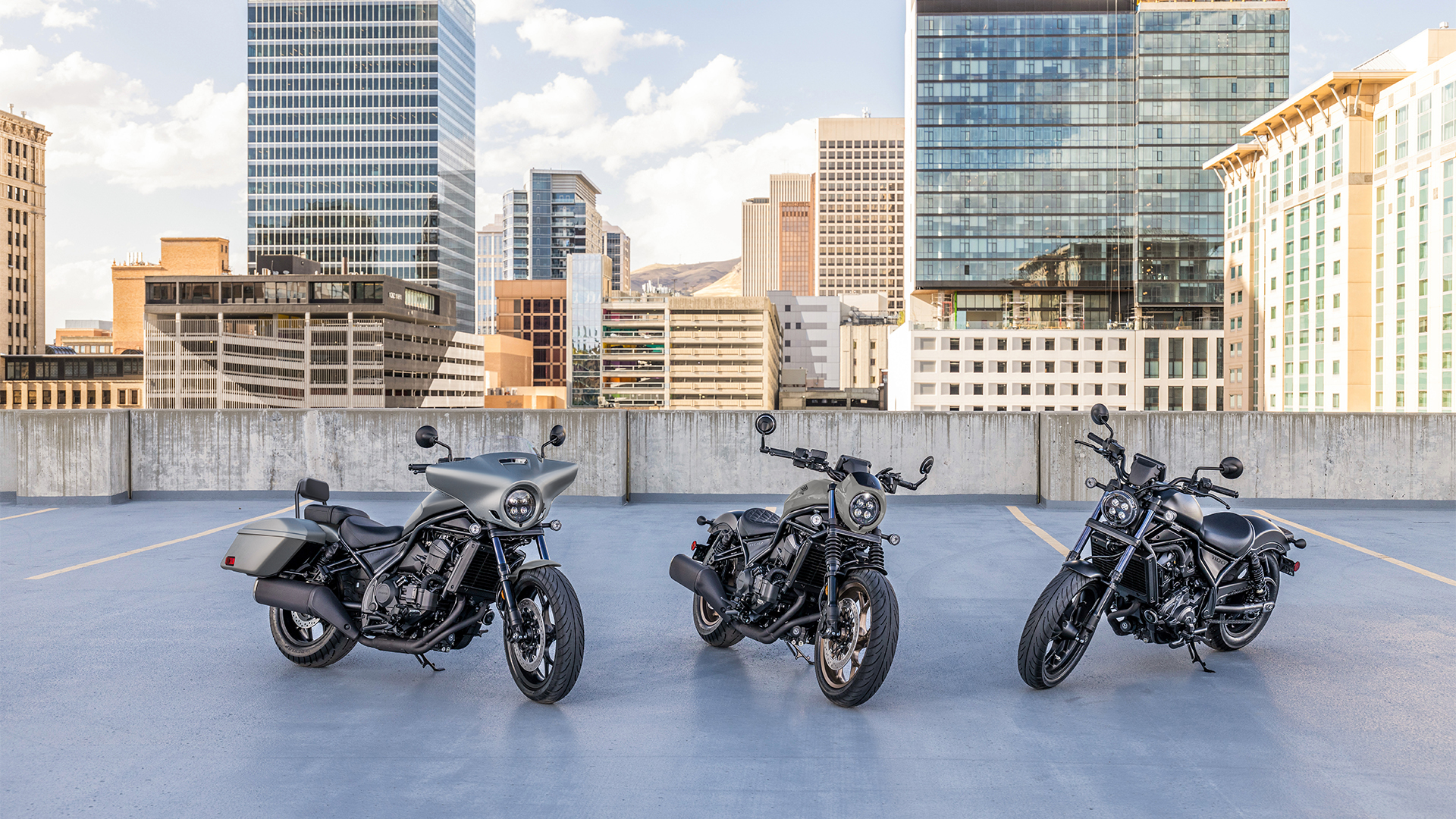Três motos CMX1100 no exterior, à frente de edifícios modernos.
