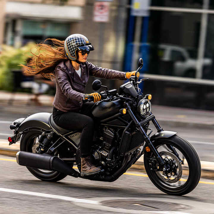Modelo em Honda CMX1100 em cenário urbano.