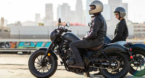 Posição lateral da Honda CMX500 Rebel com um homem e uma mulher no exterior.