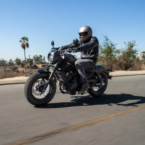 Honda CMX500 Rebel com condutor masculino num cenário de estrada. 