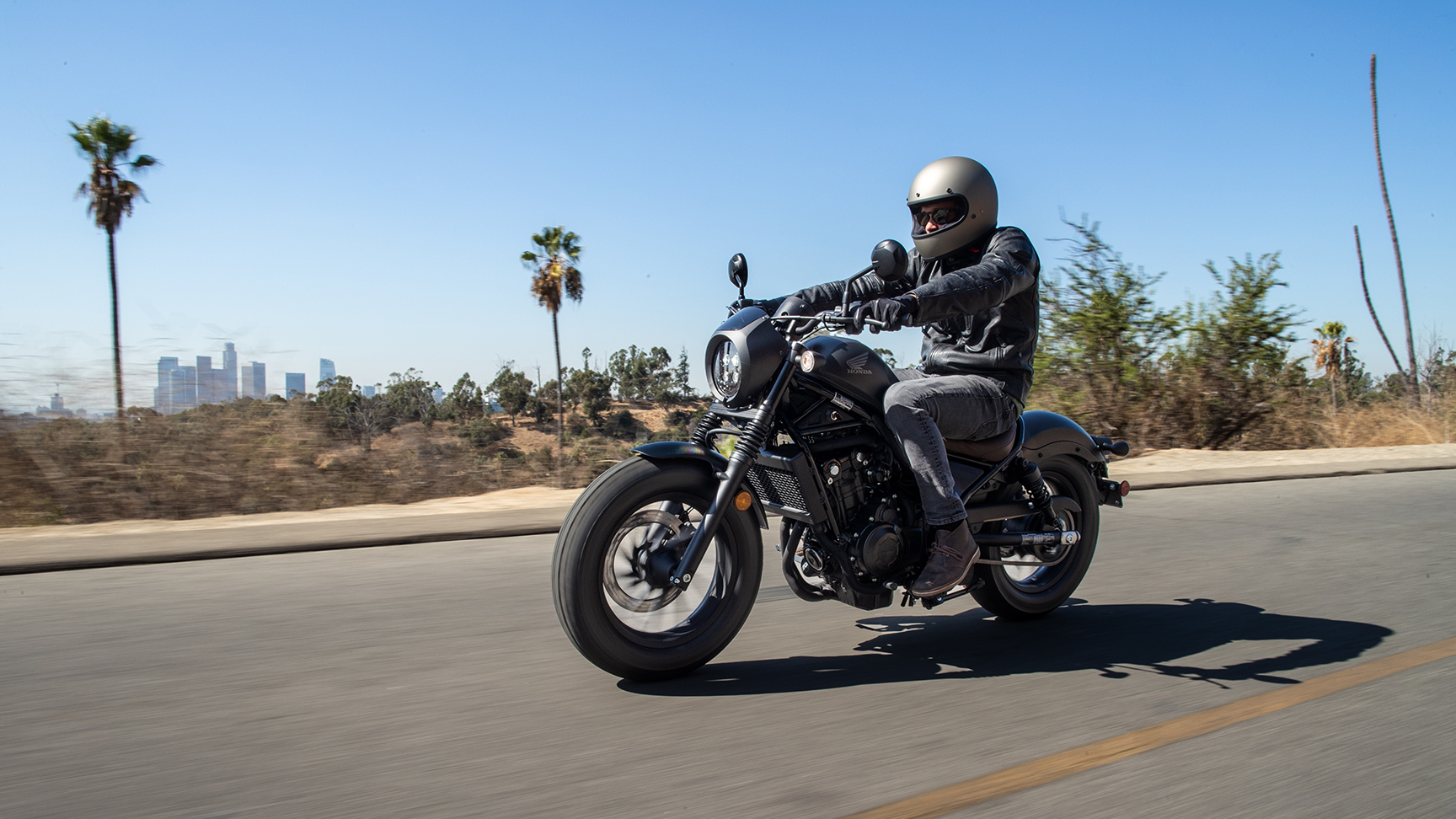 Honda CMX500 Rebel com condutor masculino num cenário de estrada. 