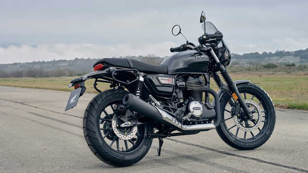 GB350S de lado, com a moto no descanso lateral, mostrando o desenho do silenciador