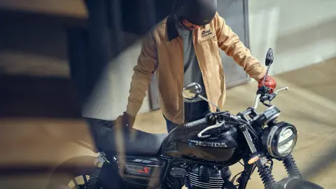 Fotografia frontal a ¾ da GB350S com condutor em cenário de café