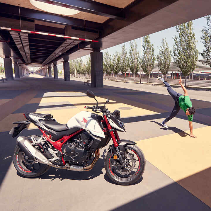 Honda CB750 Hornet debaixo de ponte com homem a fazer breakdance.