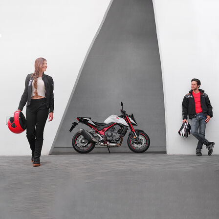 Homem e mulher inclinados ao lado de uma Honda CB750 Hornet.