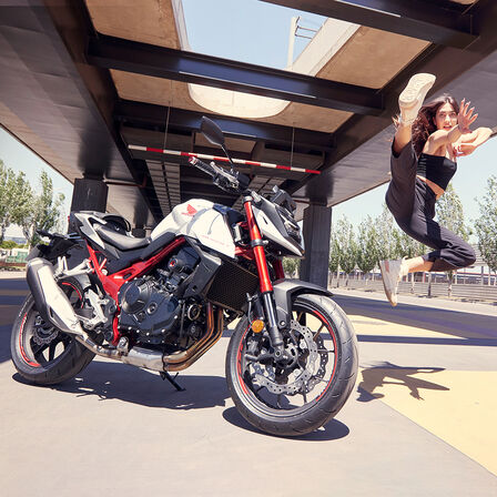 Dançarina feminina saltando no ar ao lado da Honda CB750 Hornet.