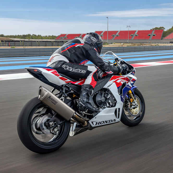 Vista traseira a três quartos da Honda CBR1000RR-R-Fireblade com condutor numa pista de corridas.
