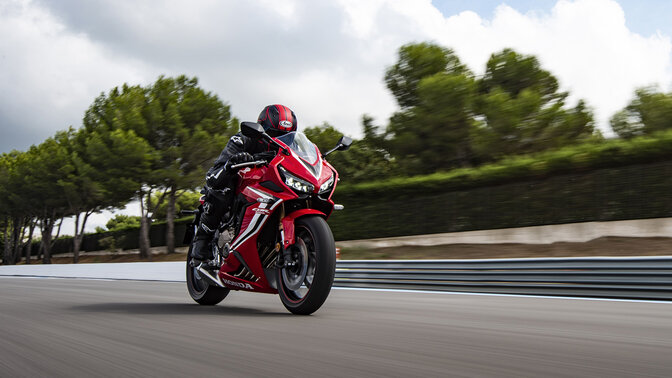 Vista frontal a ¾ da Honda CBR650R em pista de corridas com condutor