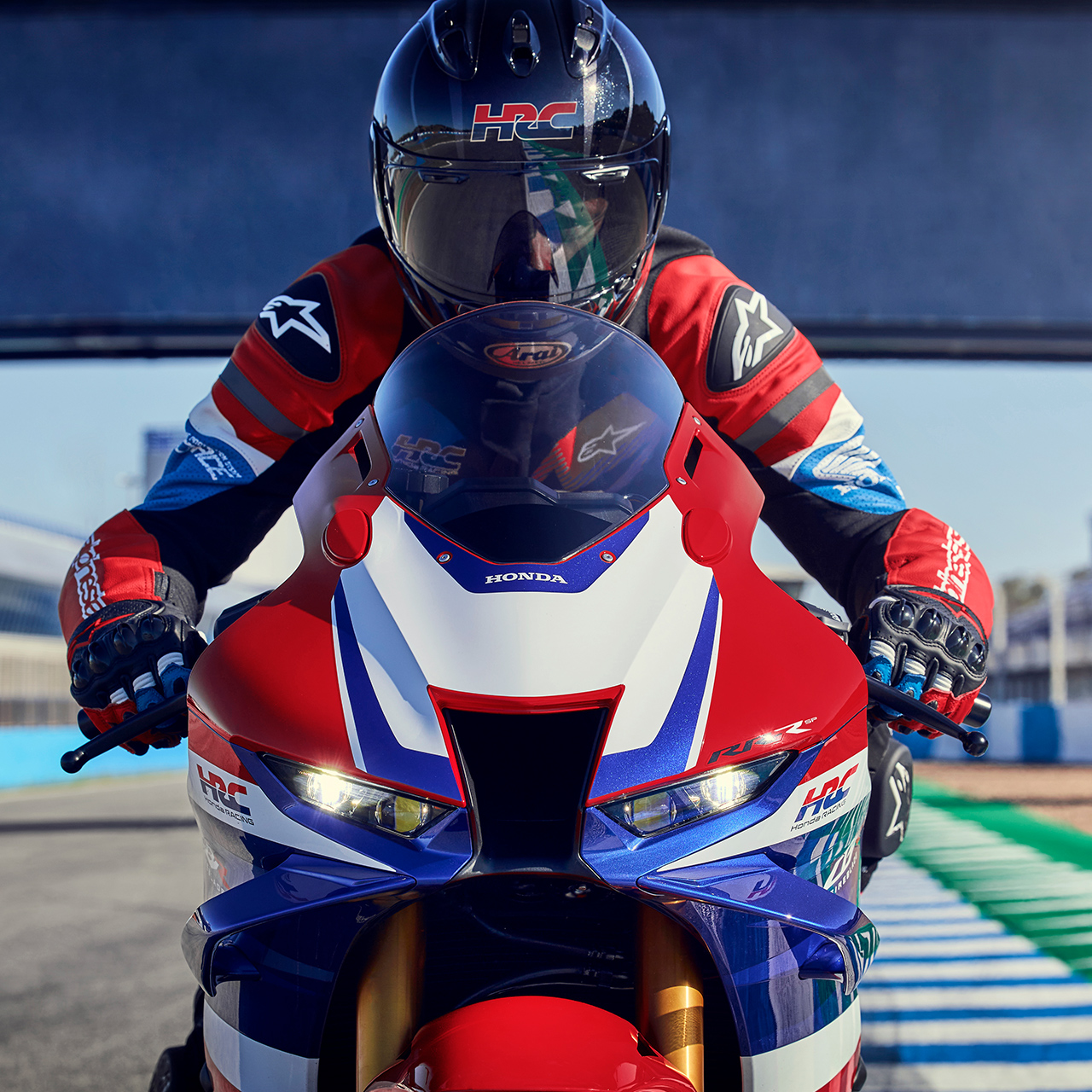 Grande plano dianteiro de piloto de frente para uma Honda CBR1000rr-r Fireblade em pista. 
