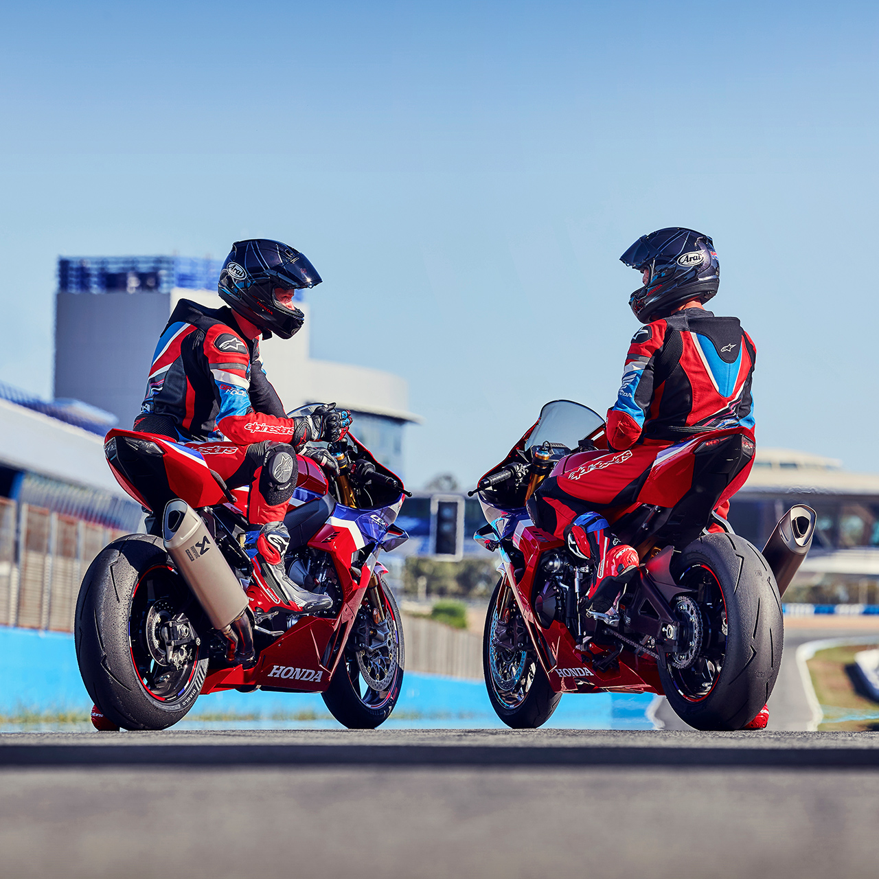 Dois pilotos virados para trás sobre uma Honda CBR1000rr-r Fireblade na pista. 
