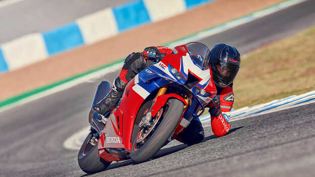 Fotografia dinâmica da Honda CBR1000rr-r Fireblade em pista com condutor a acelerar à saída de uma curva.