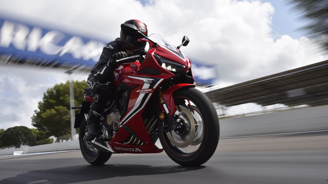 CBR650R, vista frontal lateral direita a 3 quartos com um condutor a acelerar na pista de competição