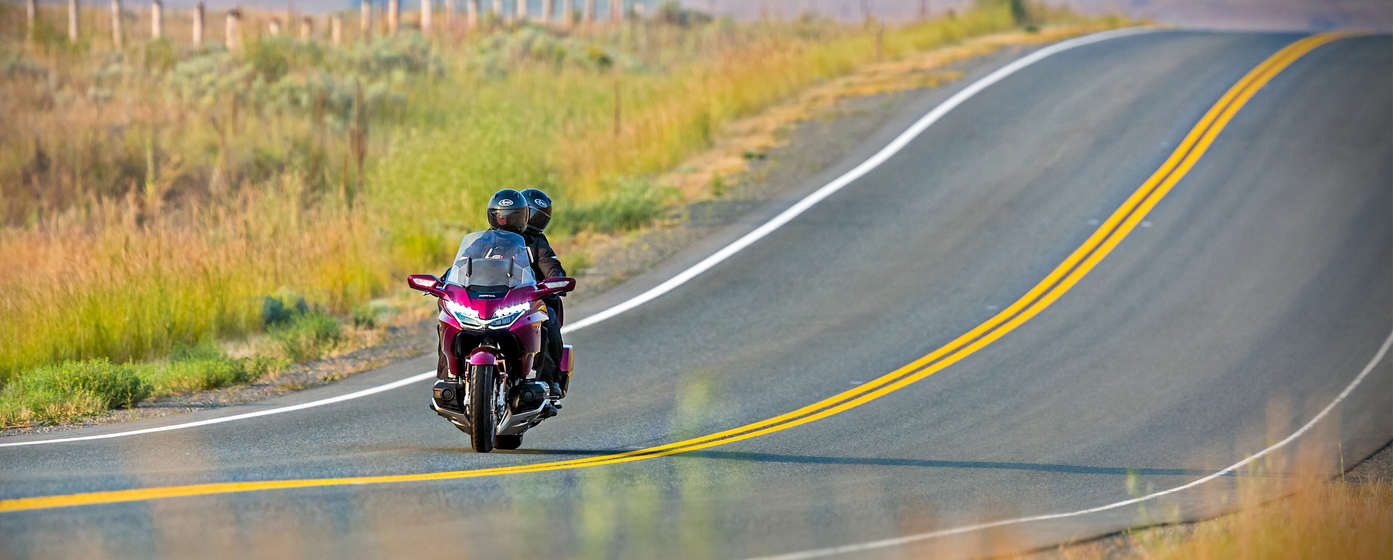 Condutor e passageiro no banco traseiro numa Honda Goldwing.