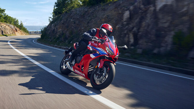 Vista frontal a ¾ da Honda CBR650R em pista de corridas com condutor