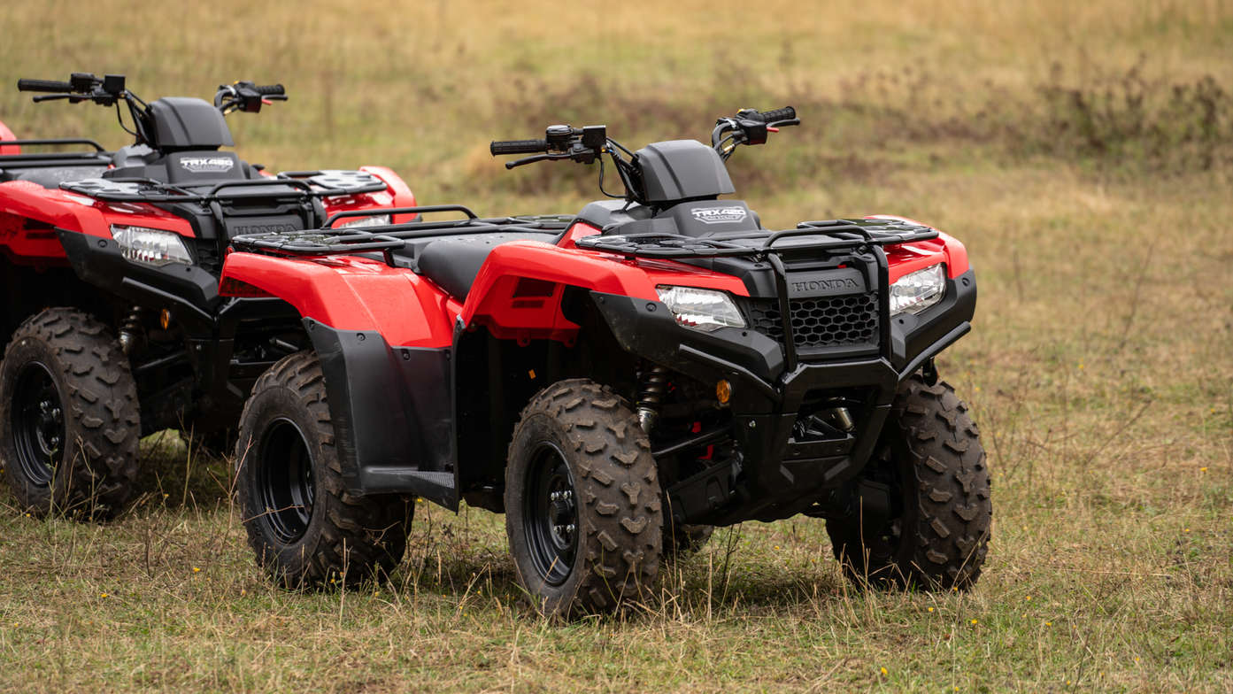 Vista frontal a três quartos do Fourtrax 420, virado para a esquerda, utilizado por modelo, num campo.